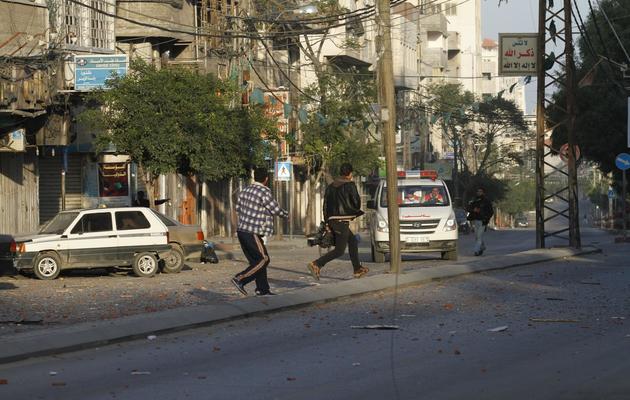 Des journalistes courent dans une rue de Gaza après une frappe aérienne israélienne visant des bureaux d'une chaîne de télévision, le 18 novembre 2012 [Mohammed Abed / AFP]