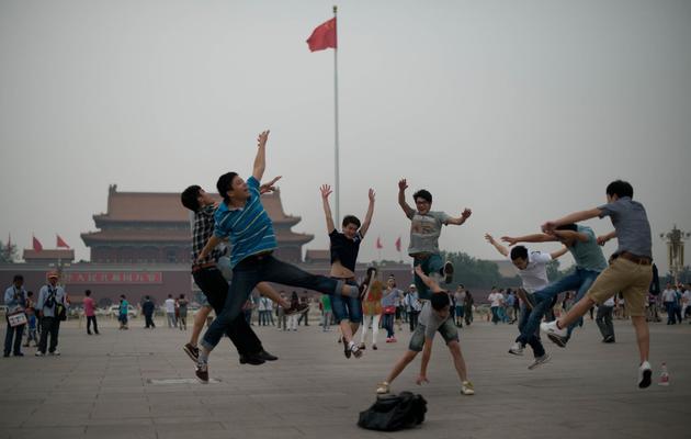 Des touristes sautent en l'air pendant que leurs amis les prennent en photo sur la place Tiananmen à Pékin, le 4 juin 2013 [Ed Jones / AFP]