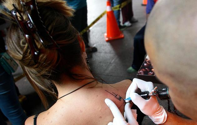 Une femme se fait tatouer la signature de l'ancien président Hugo Chavez, le 8 avril 2013 à Caracas [Geraldo Caso / AFP]