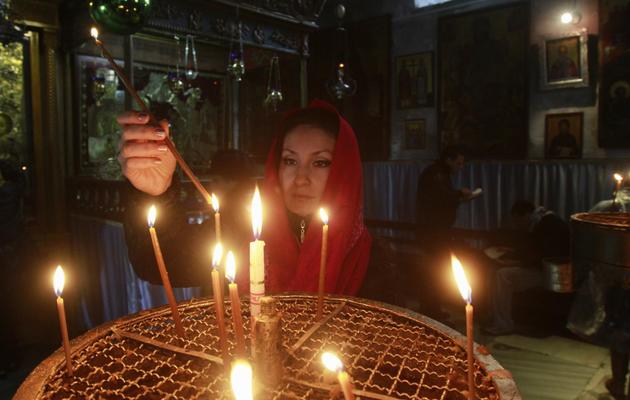 Un femme allume des bougies à l'église de la Nativité, à Bethléem, le 20 décembre 2012 [Musa al Shaer / AFP]