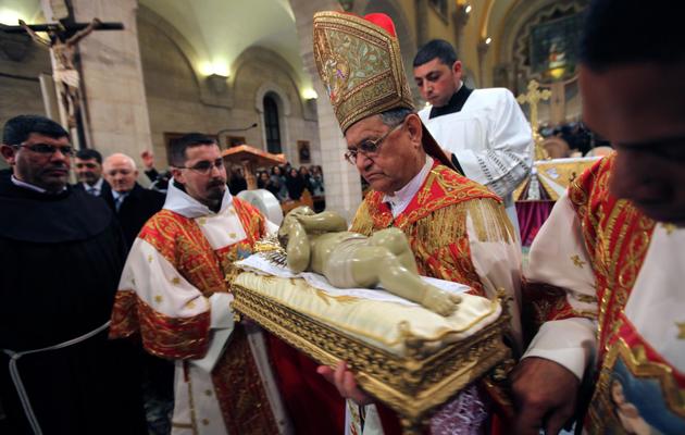 Le patriarche latin de Jérusalem, Mgr Fouad Twal, porte une réplique de l'enfant Jésus, à Bethléem, le 25 décembre 2012 [Abed al-Hashlamoun / Pool/AFP]