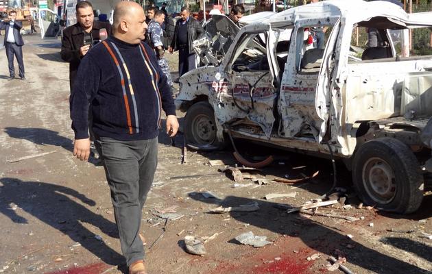 Un homme regarde la carcasse d'une voiture piégée lancée contre le quartier général de la police à Kirkouk, le 3 février 2013 [Marwan Ibrahim / AFP]