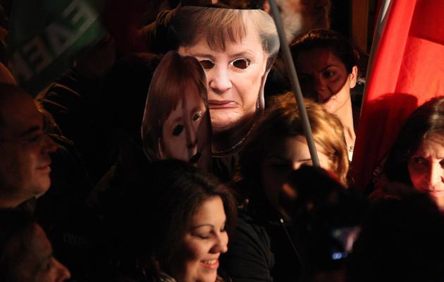 Des manifestants brandissent un masque représentant la chancelière allemande Angela Merkel le 19 mars 2013 à Nicosie [Barbara Laborde / AFP]