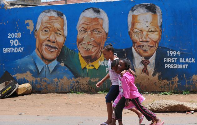 Des habitants de Soweto, près de Johannesburg, marche devant un mur en hommage à l'ancien président Nelson Mandela, le 10 décembre 2012 [Alexander Joe / AFP]