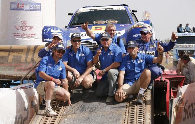 Jean-Louis Schlesser (en haut à droite) fête avec son équipe sa victoire dans la 5e édition du rallye Africa Eco Race, le 9 janvier 2012. [Mamadou Toure Behan / AFP]