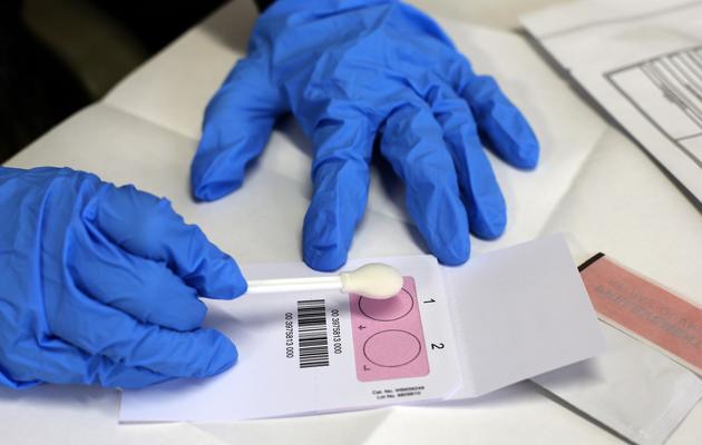 Un agent collecte des échantillons d'ADN, lors d'une reconstitution au commissariat de Poissy le 25 janvier 2013 [Thomas Samson / AFP]