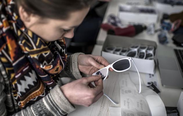 Une employée de Lulu Frenchie décore les verres d'une paire de lunettes, le 28 février 2013 au siège de la société à Lyon [Jeff Pachoud / AFP]