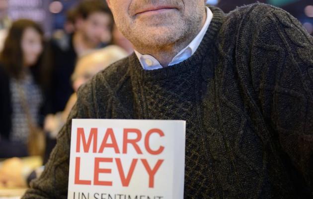 L'écrivain Marc Lévy pose avec son roman, "Un sentiment plus fort que la peur", au Salon du livre de Paris le 23 mars 2013 [Eric Feferberg / AFP]