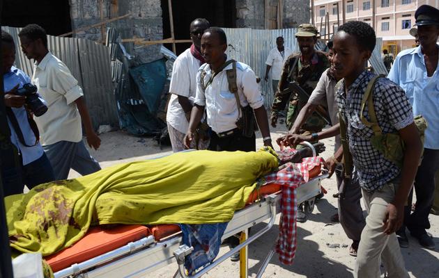 Des policiers et des secouristes somaliens transportent le corps d'une victime d'un attentat suicide à Mogadiscio le 5 mai 2013 [Mohamed Abdiwahab / AFP]