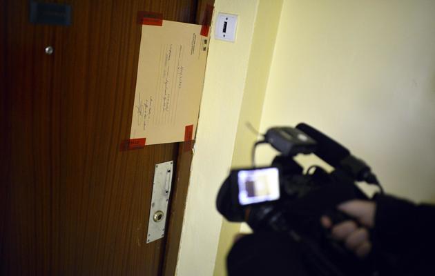 Un journaliste filme à Saint Priest, près de Lyon, les scellés laissés par la police sur la porte d'un appartement où un père est soupçonné d'avoir tué ses enfants, le 19 mai 2013 [Jeff Pachoud / AFP]