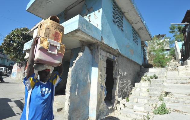 Un homme passe le 11 janvier 2013 à côté d'une maison de Port-au-Prince détruite par le séisme de janvier 2010 [Thony Belizaire / AFP]