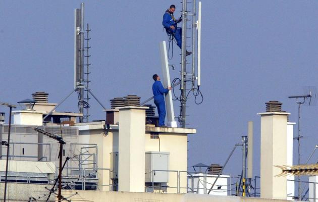 Des techniciens installent des relais téléphoniques sur le toit d'un immeuble parisien, en 2003 [Jacques Demarthon / AFP/Archives]
