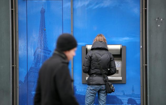 Une femme retire de l'argent dans un distributeur à Paris [Loic Venance / AFP/Archives]